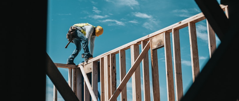 man in yellow shirt and blue denim jeans jumping on brown wooden railings under blue and