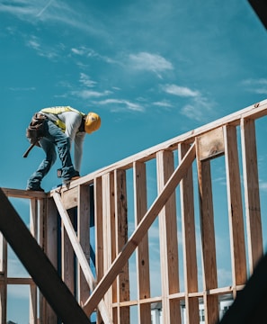 man in yellow shirt and blue denim jeans jumping on brown wooden railings under blue and