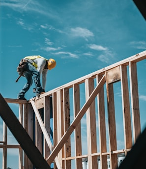 man in yellow shirt and blue denim jeans jumping on brown wooden railings under blue and