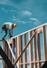 man in yellow shirt and blue denim jeans jumping on brown wooden railings under blue and