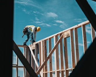 man in yellow shirt and blue denim jeans jumping on brown wooden railings under blue and