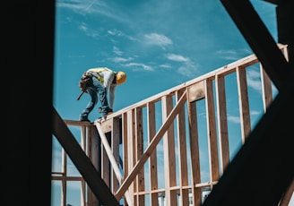 man in yellow shirt and blue denim jeans jumping on brown wooden railings under blue and