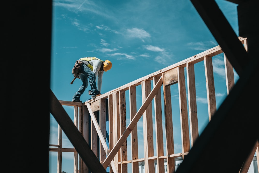 homme en chemise jaune et jean bleu sautant sur des balustrades en bois marron sous bleu et