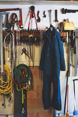 A heavy-duty metal workbench in a bright, organized garage with tools neatly arranged on a pegboard behind it.