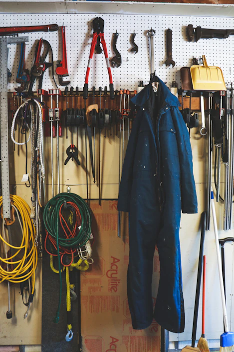 A heavy-duty metal workbench in a bright, organized garage with tools neatly arranged on a pegboard behind it.