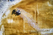 Aerial shot of mining trucks moving through rugged African terrain at sunrise.