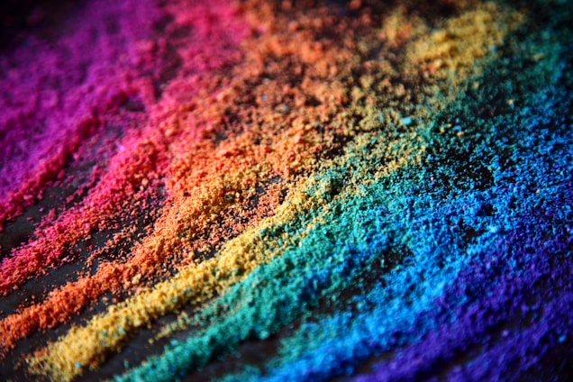 Vivid, multicolored powder arranged in diagonal lines, creating a vibrant gradient from red to violet.