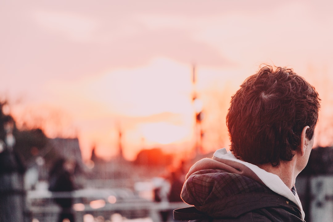 man in brown jacket looking at the sunset