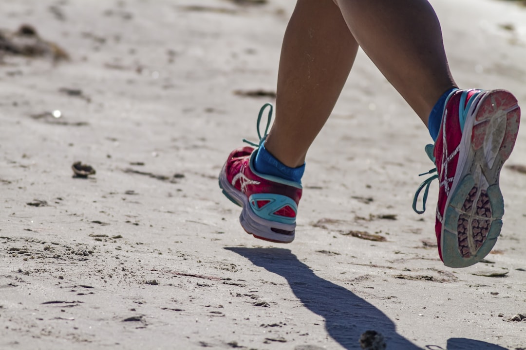 person wearing blue and white sneakers, Runner in full stride on the beach