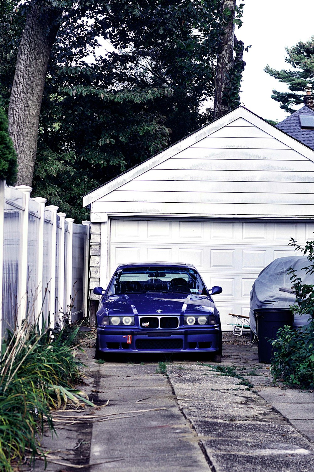 blue bmw m 3 parked beside white wooden fence