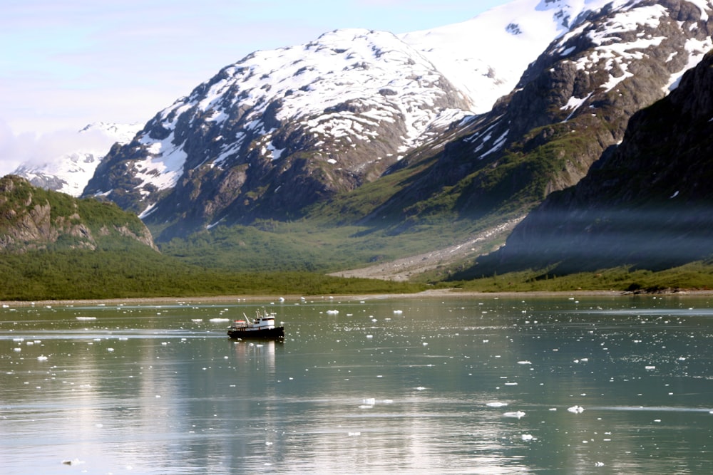 person riding on boat on lake near snow covered mountain during daytime