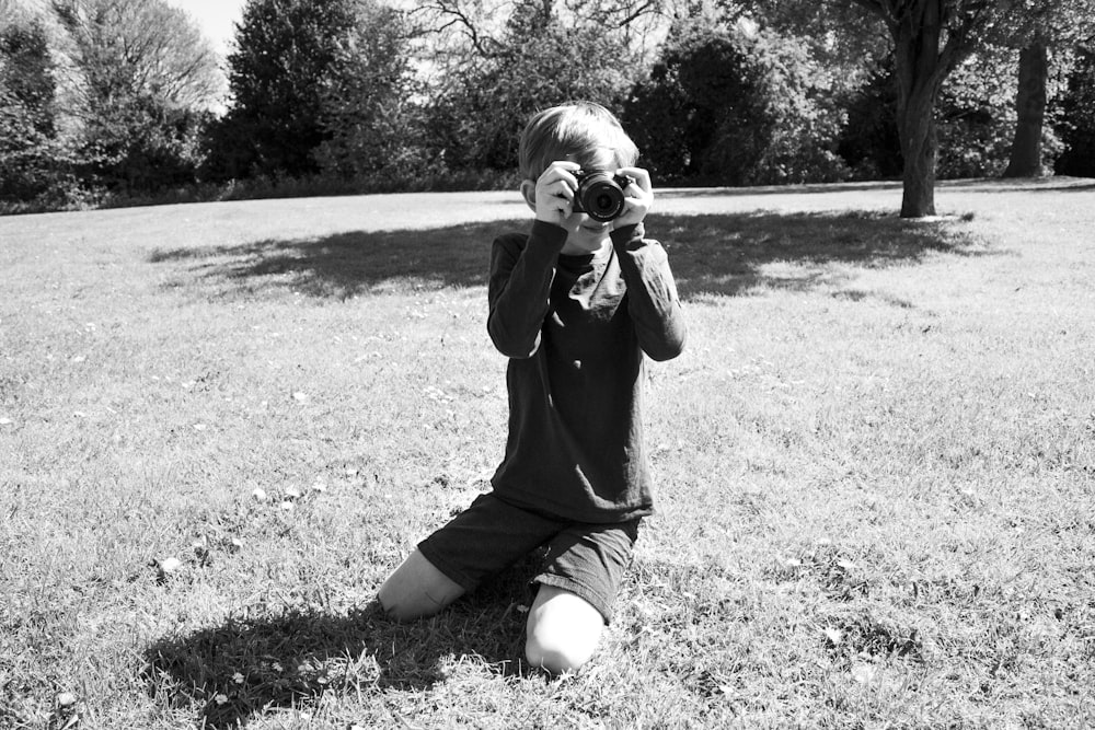 grayscale photo of woman in black long sleeve shirt holding camera