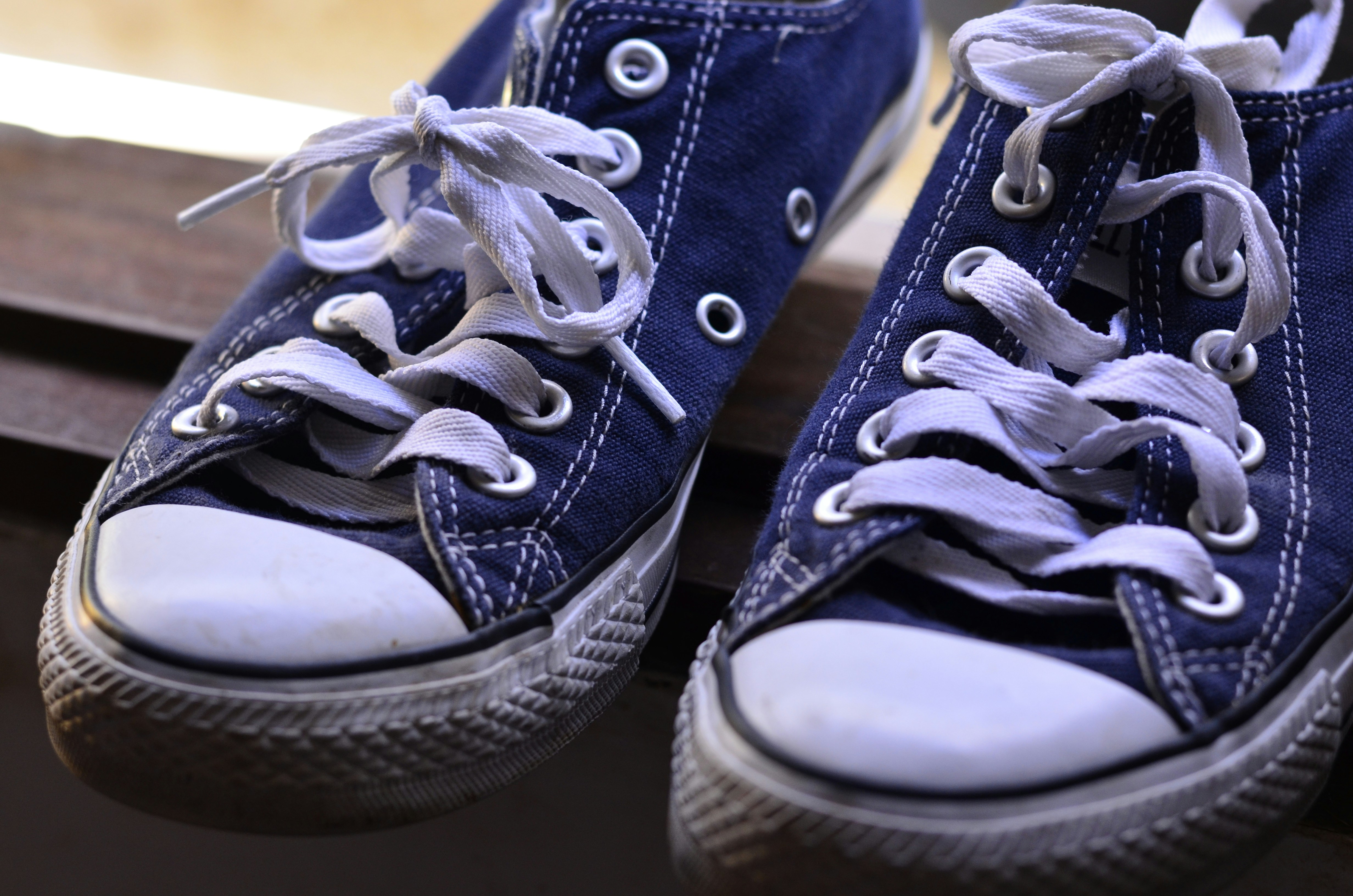 White canvas low-top sneakers with aqua blue accent stripe on white studio background