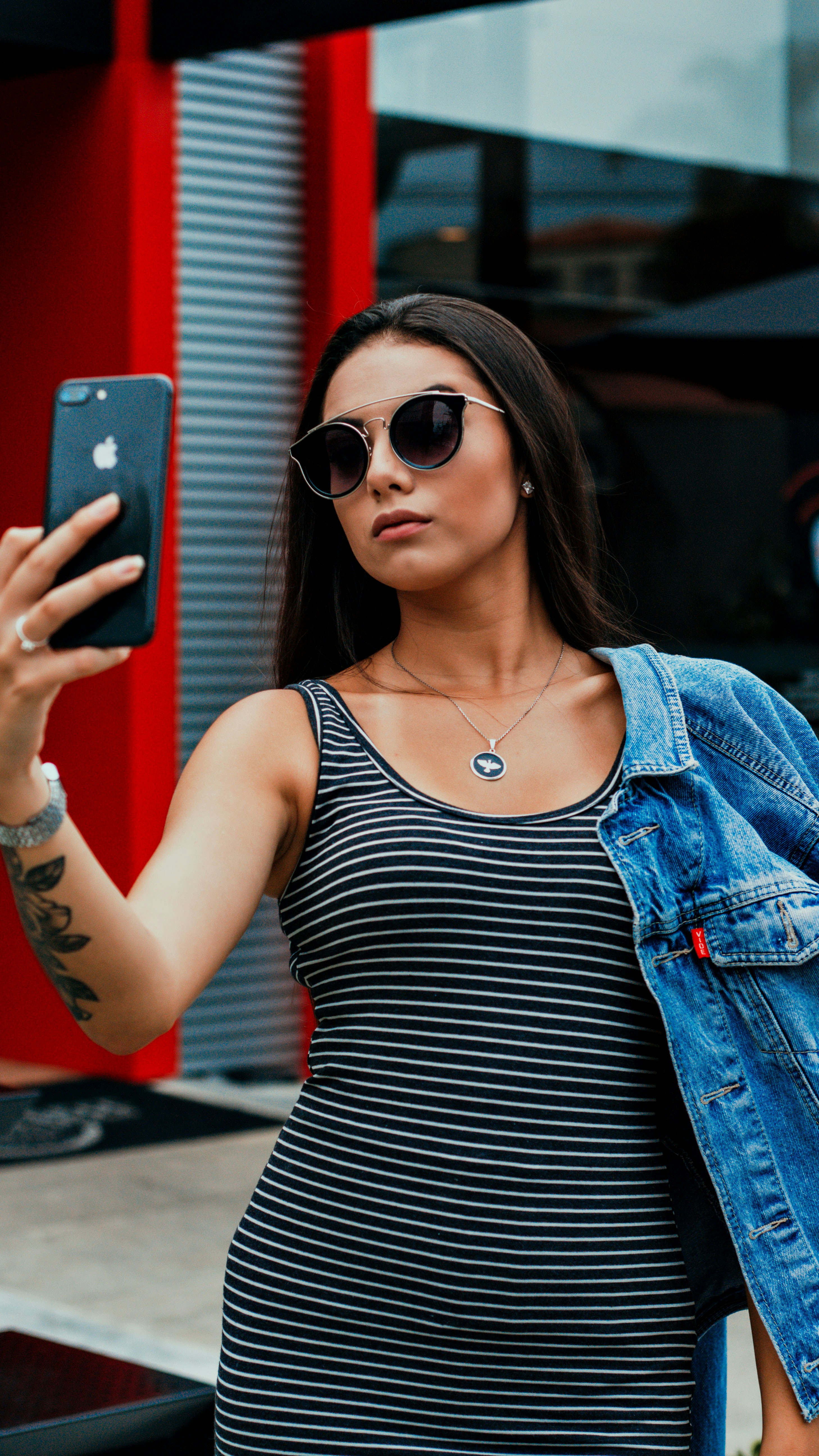 Wanita dengan Tank Top Garis Hitam Dan Putih Memegang iPhone 7 Plus Merah