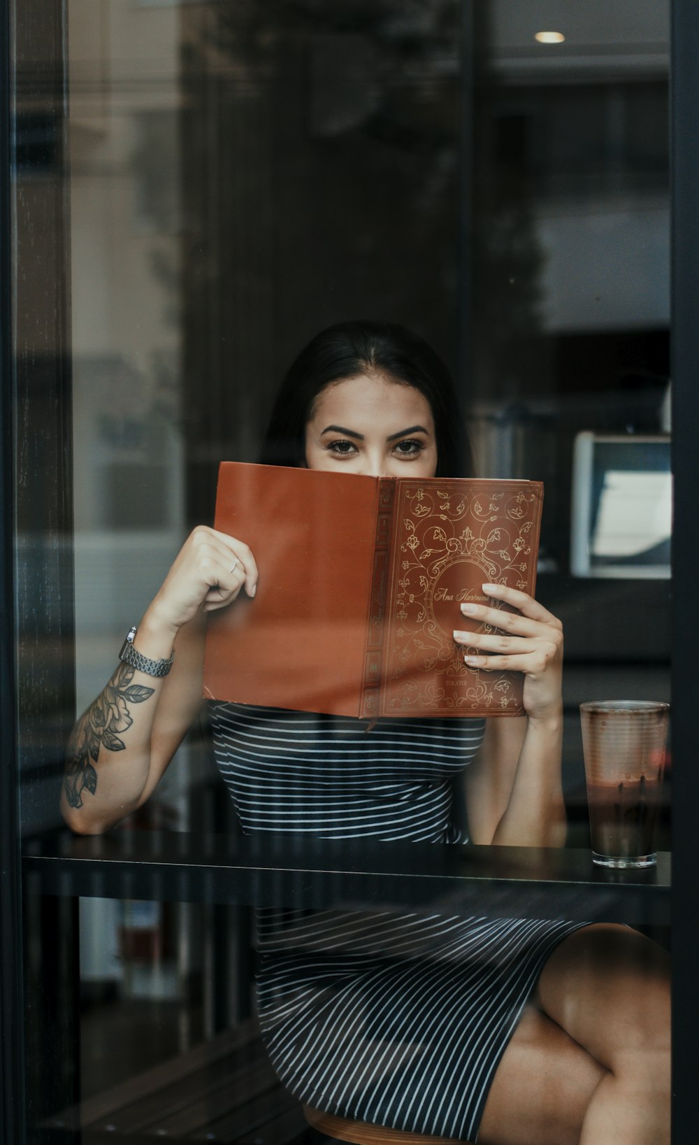 woman in black and white stripe shirt holding brown leather book