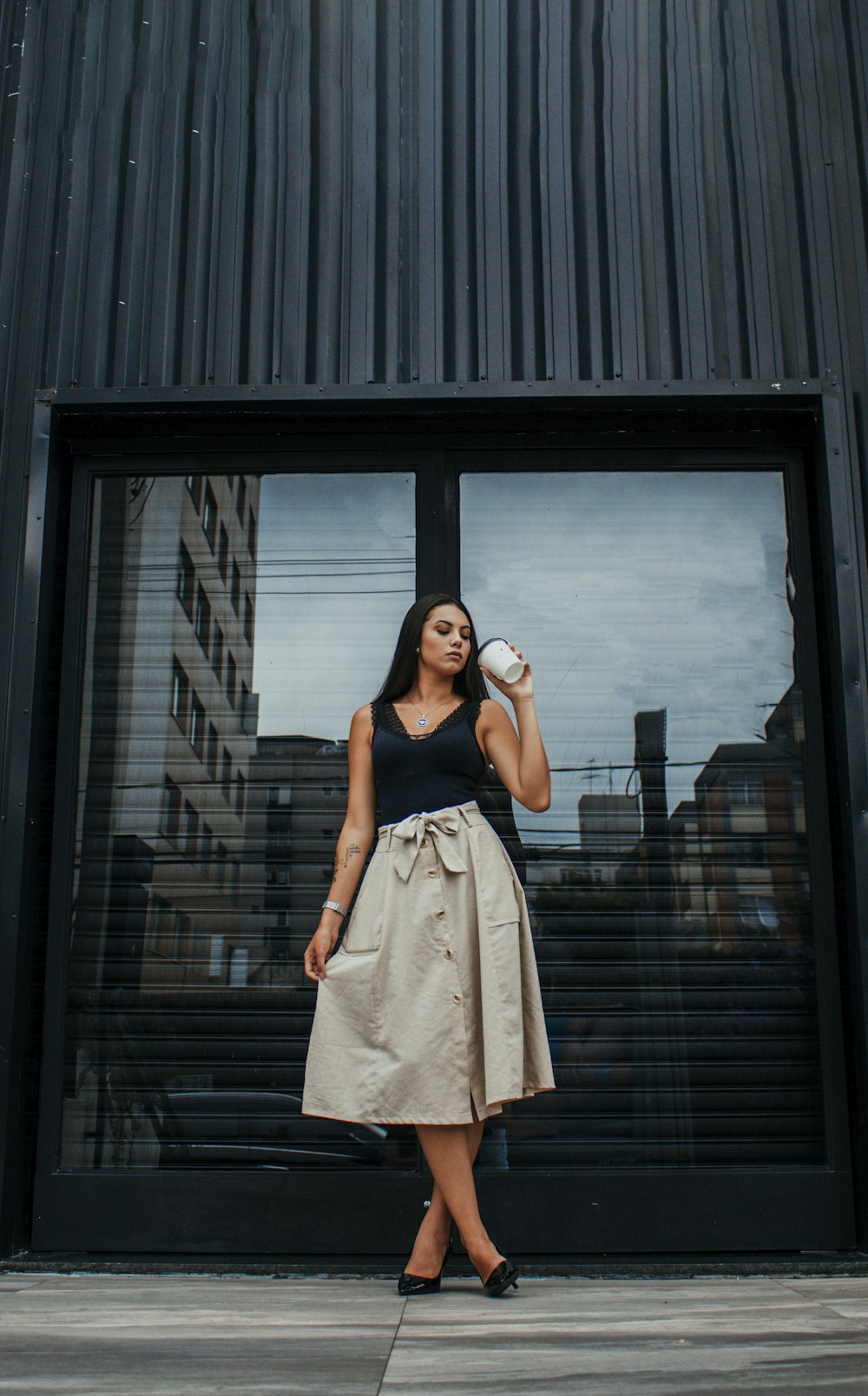 woman in beige sleeveless dress standing beside black wooden door