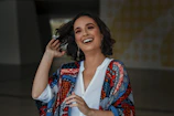 Lifestyle shot of a woman laughing outdoors, showcasing elegant gold hoop earrings.