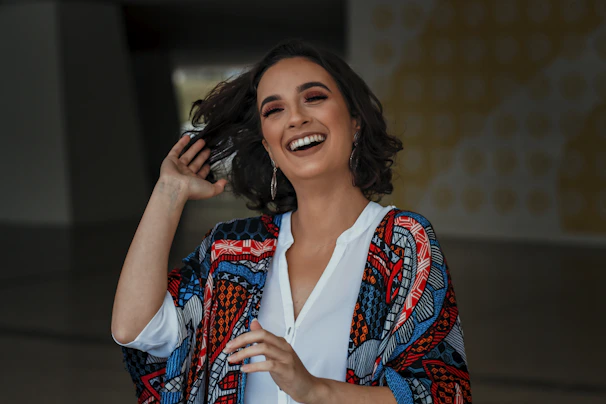 A plus size woman laughing, wearing a trendy plus size outfit with bold patterns and soft pink accents.