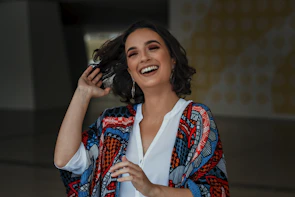 Lifestyle shot of a woman laughing outdoors, showcasing elegant gold hoop earrings.