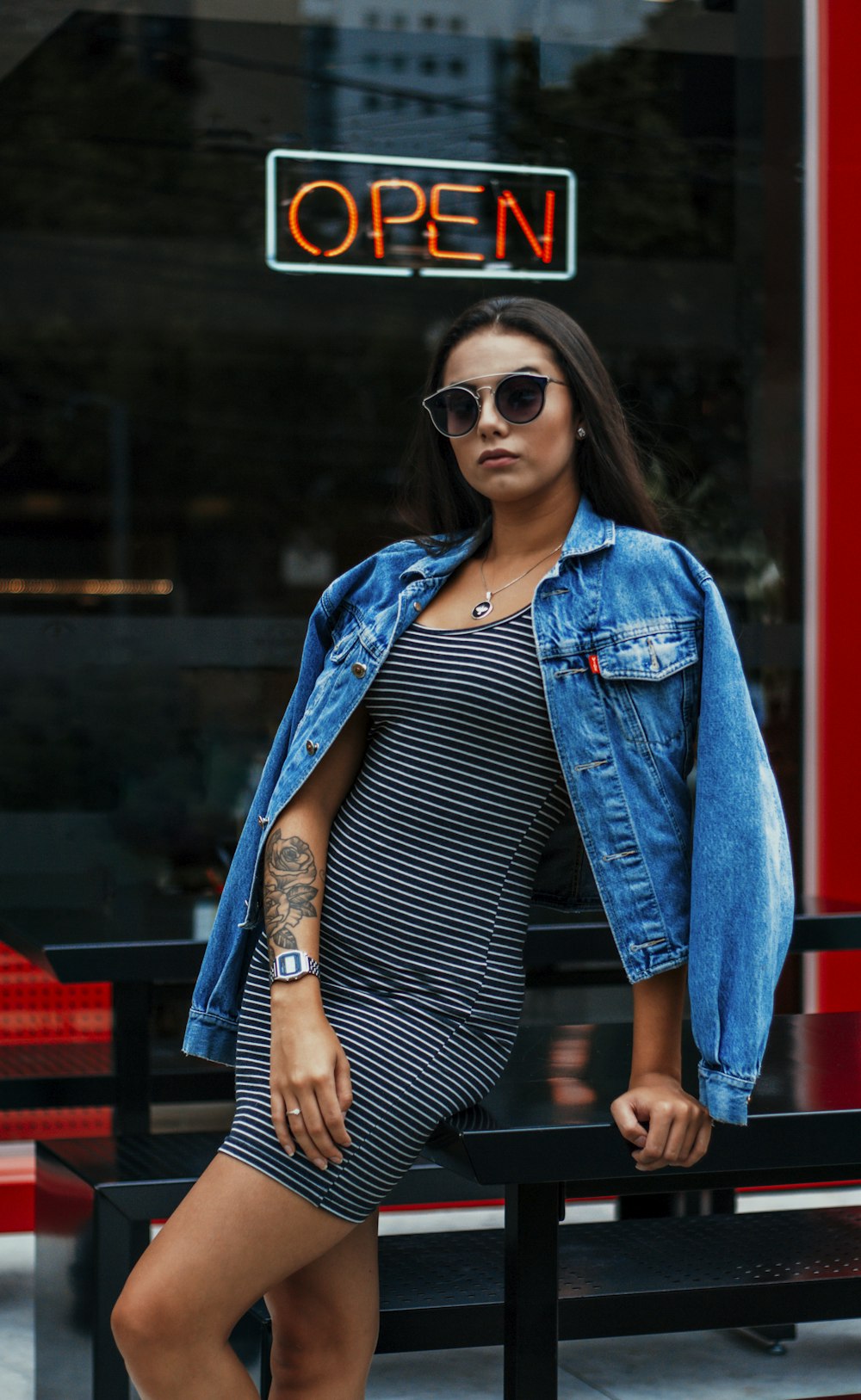 woman in black and white striped shirt and blue denim jacket wearing black sunglasses