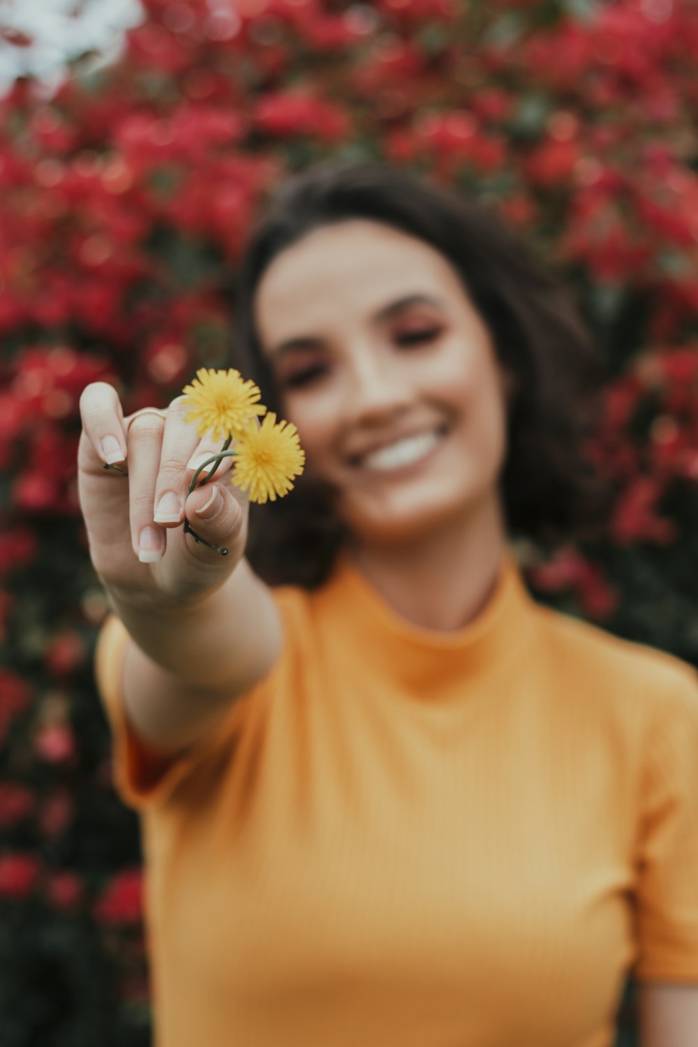 a woman in a yellow shirt holding a yellow flower