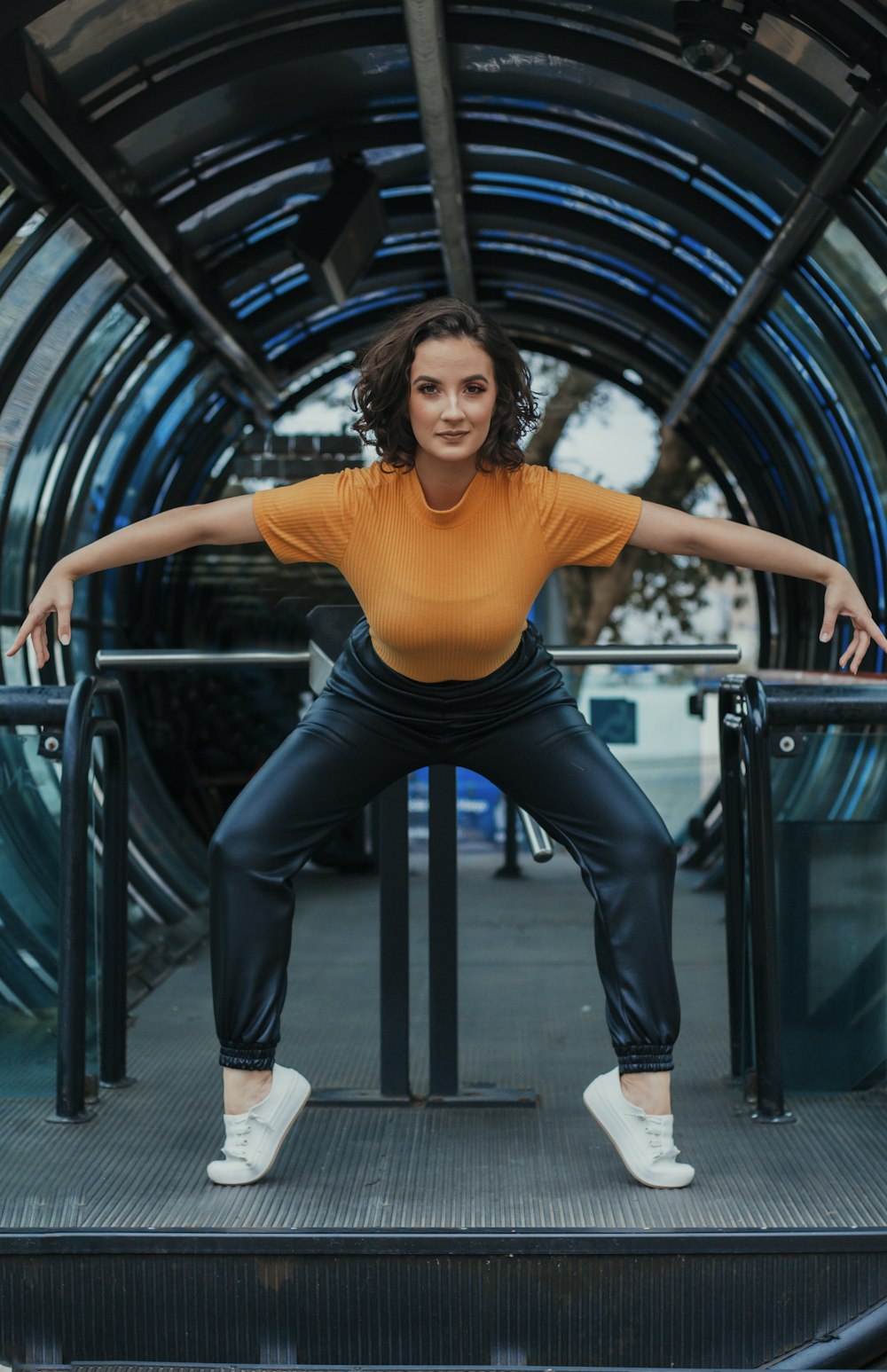 woman in yellow shirt and black pants sitting on black metal railings