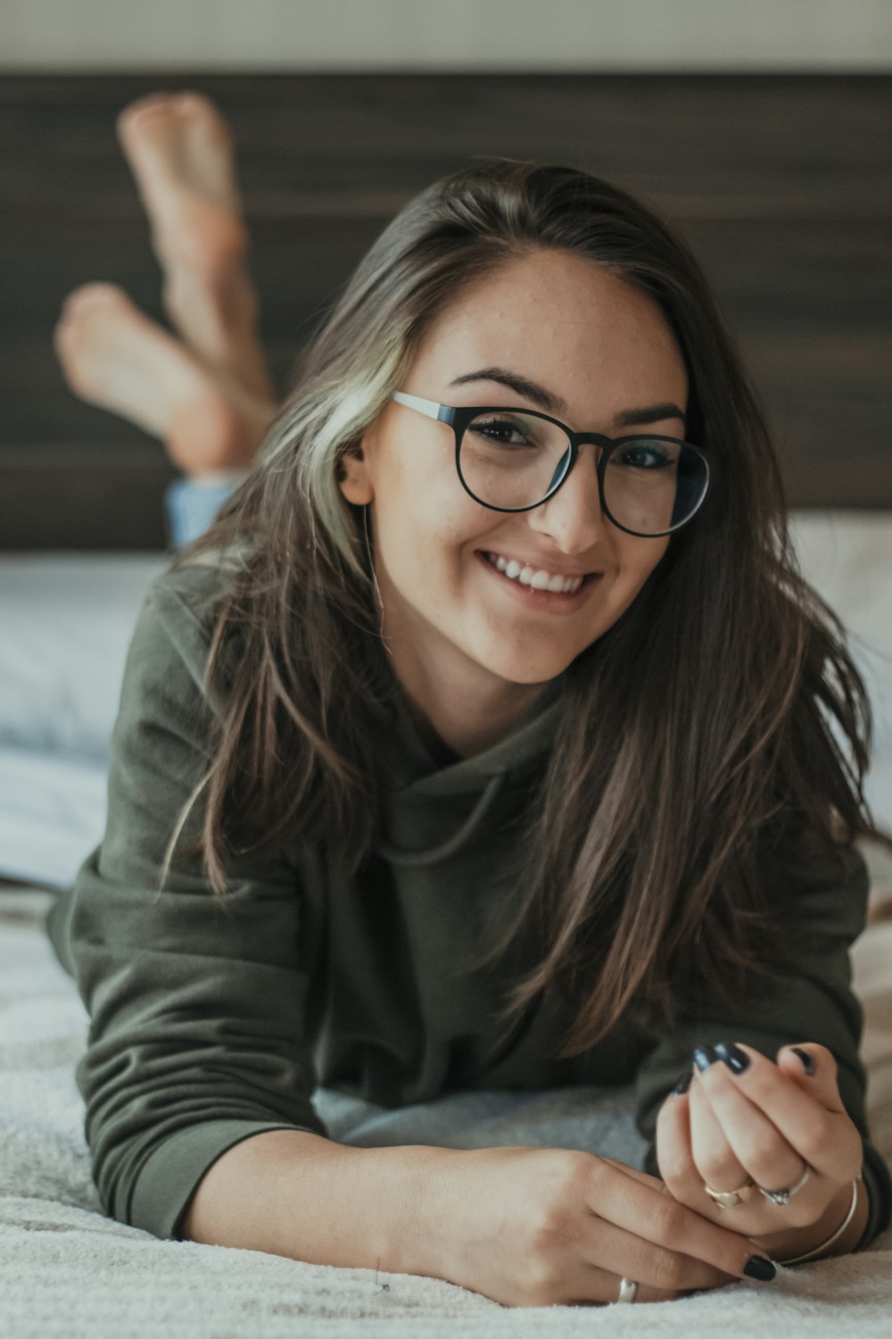 Femme avec des lunettes à monture noire et une chemise à manches longues grise