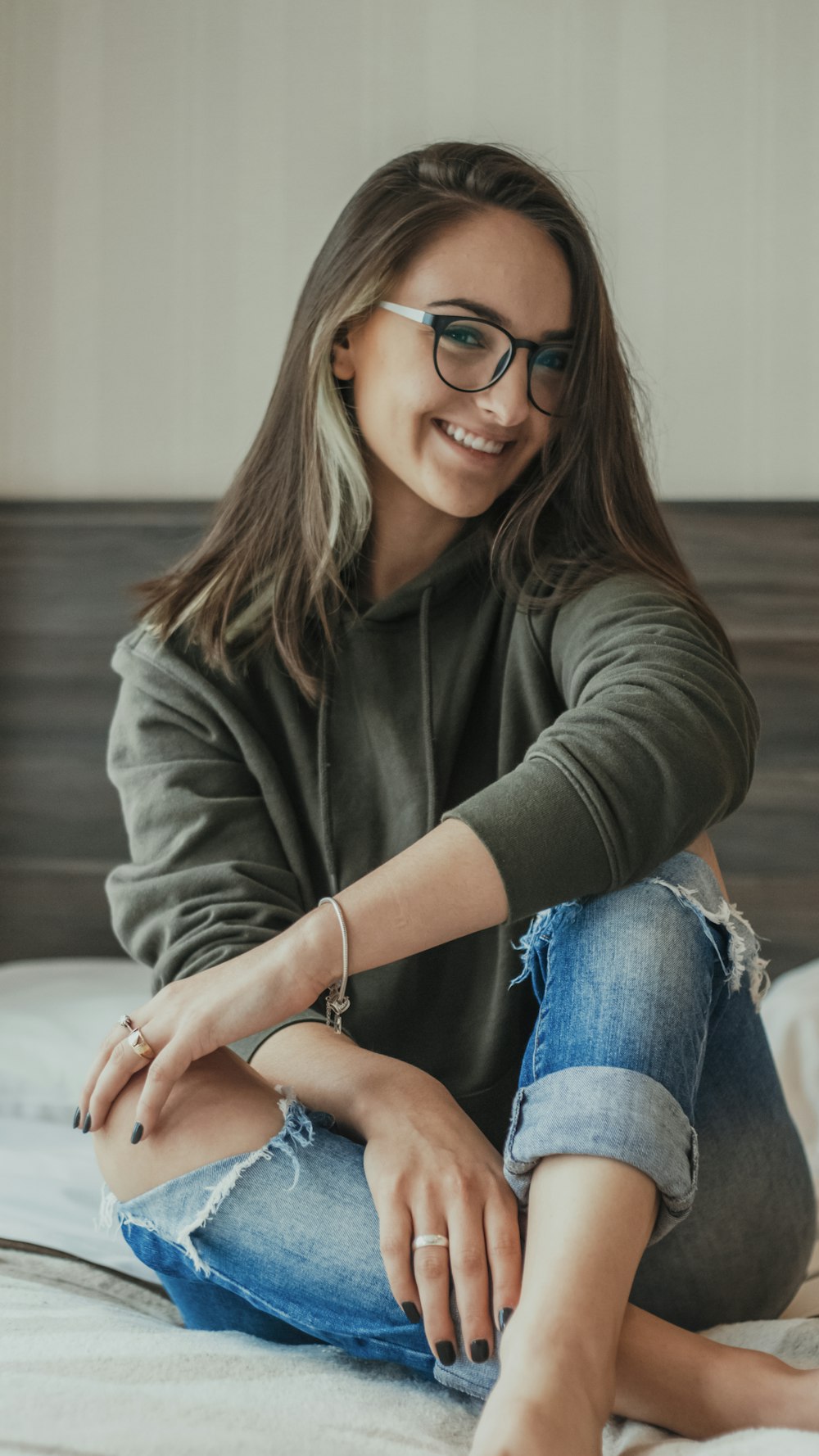 Frau in grauem Pullover und blauer Jeans mit schwarz gerahmter Brille