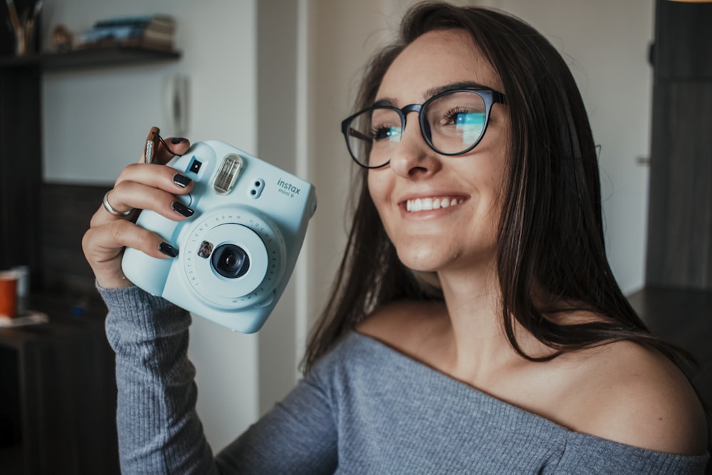 woman in gray off shoulder shirt holding gray and black camera