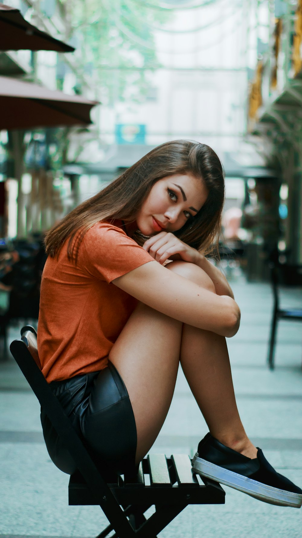 Frau in orangefarbenem Hemd und blauen Jeansshorts sitzt auf der Bank