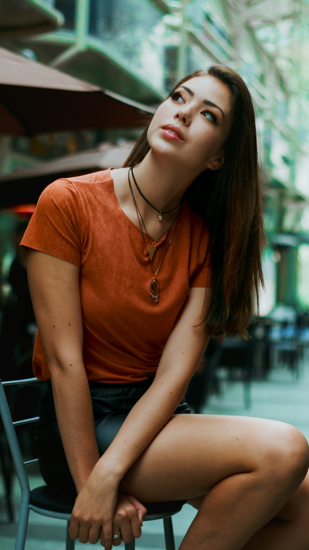 woman in orange crew neck t-shirt and blue denim shorts sitting on blue bench during