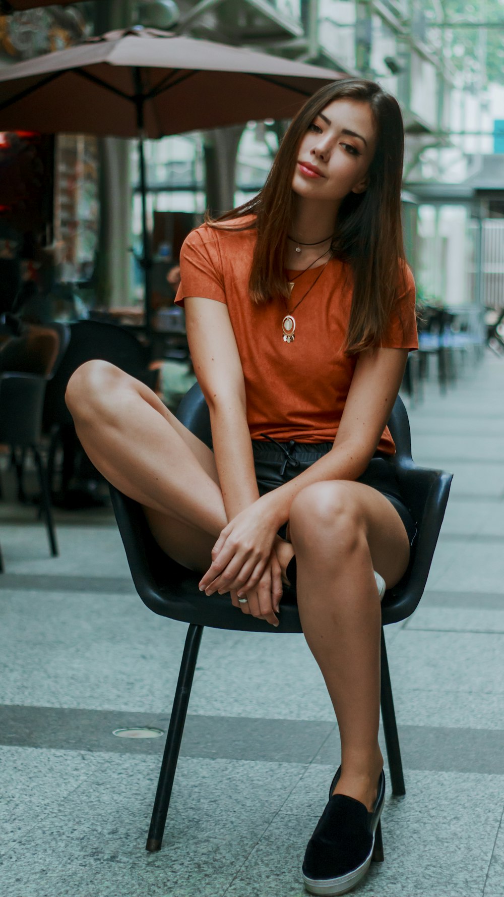 mulher na t-shirt laranja do pescoço da tripulação sentada na cadeira preta