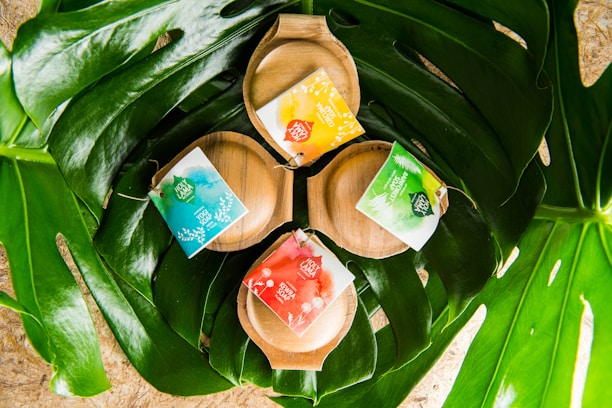 A neatly arranged set of Herbal Clean soaps on a wooden tray beside green leaves.