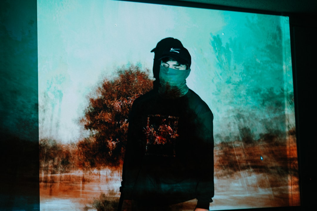 man in black crew neck shirt standing near green trees