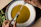 Close-up of hands sprinkling a colorful spice mix over a steaming bowl of soup.