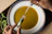 Close-up of hands sprinkling a colorful spice mix over a steaming bowl of soup.