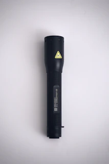 Close-up of hands holding a compact emergency flashlight with neon orange accents.