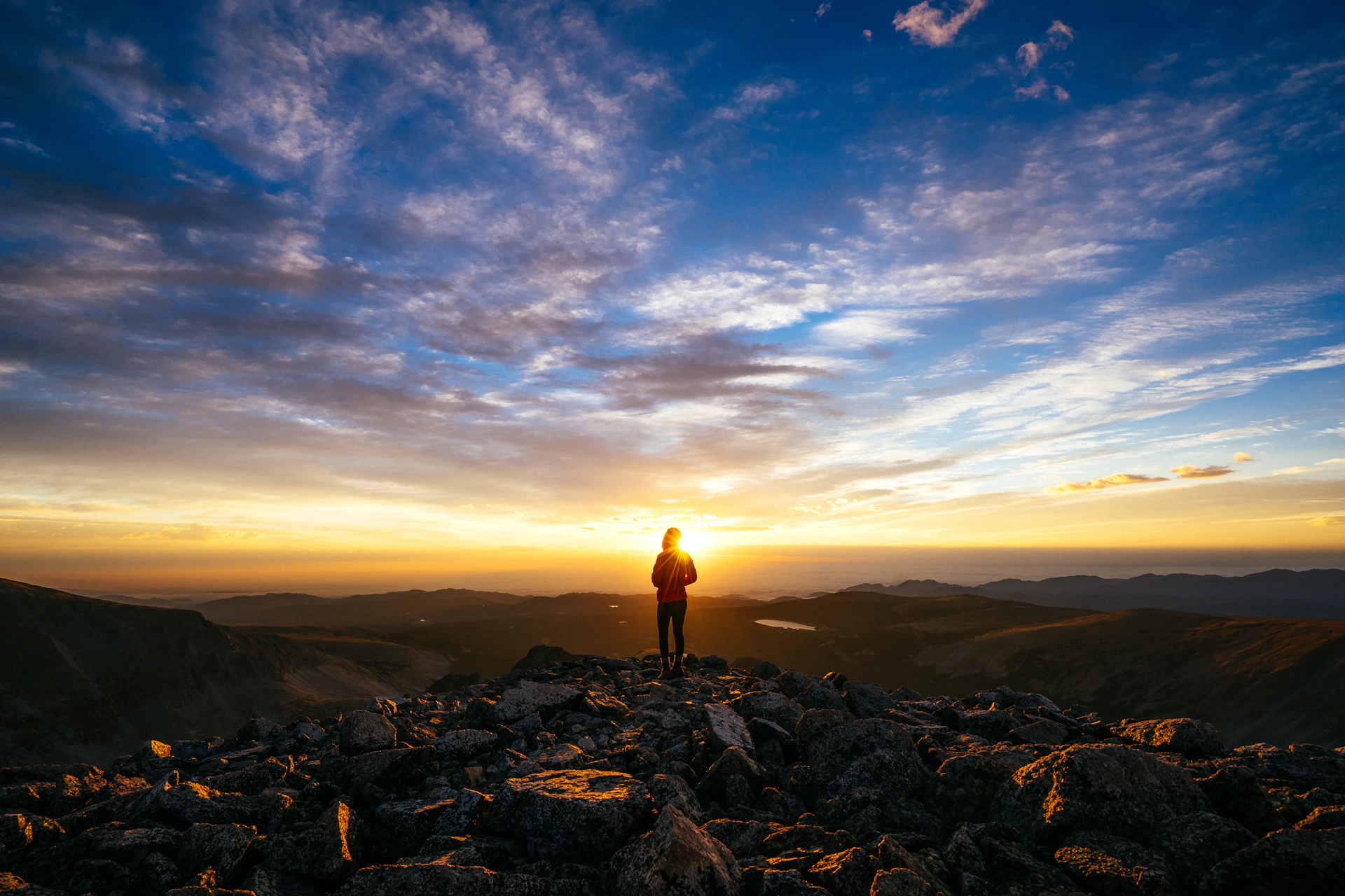 person standing on rocky mountain under blue sky during daytime