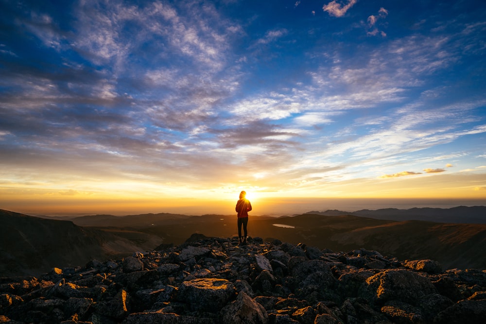 person standing on rocky mountain under blue sky during daytime