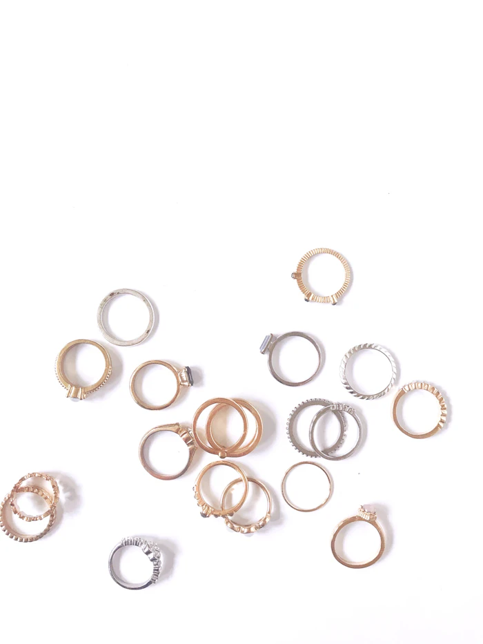 Silver and gold minimalist rings on a white surface