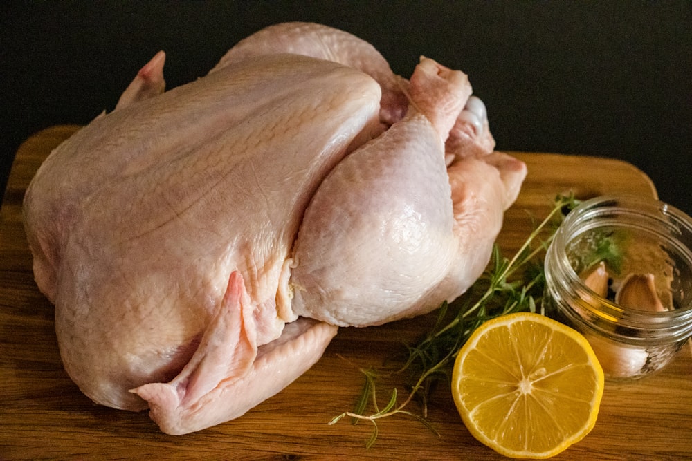 carne de pollo cruda en una tabla de cortar de madera marrón