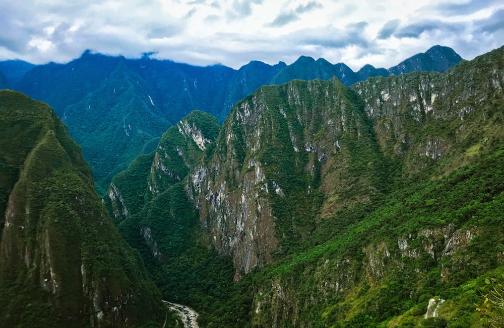 montanhas verdes e marrons sob nuvens brancas e céu azul durante o dia