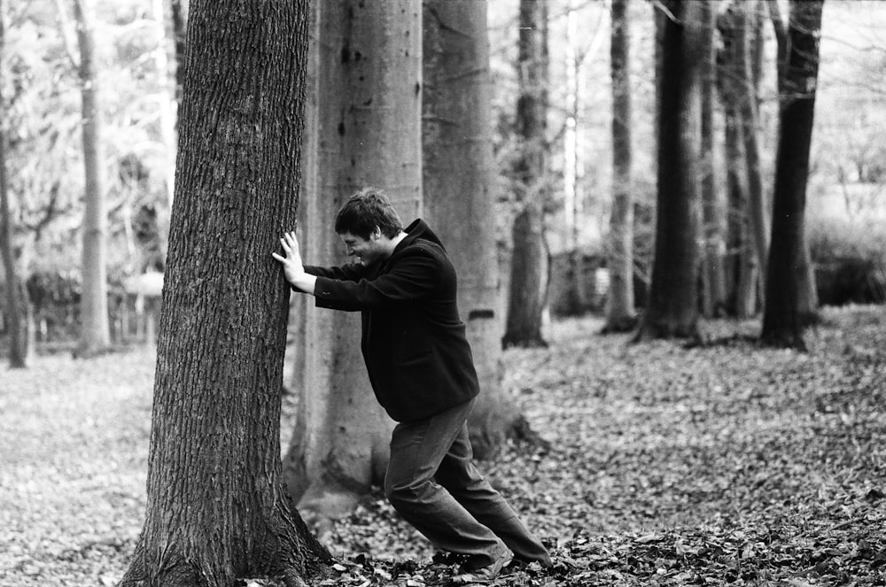 man in black jacket and pants climbing on tree