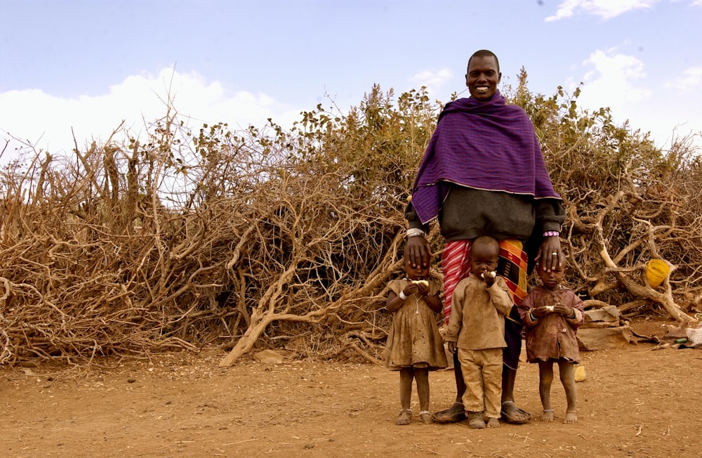 man in purple hoodie standing beside brown bare tree during daytime