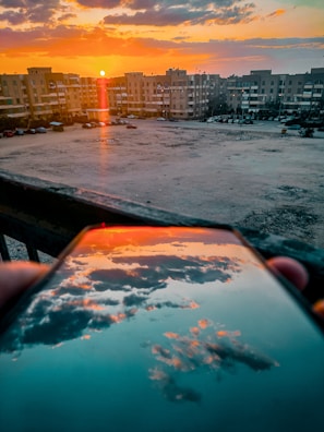 A vibrant sunset over a city skyline captured with a smartphone.