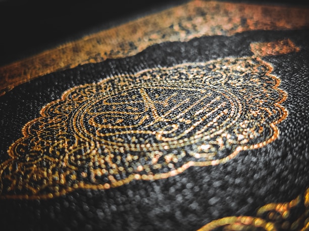 Intricate golden Arabic calligraphy adorns an embossed dark cover, with a rich texture that highlights the detailed craftsmanship.