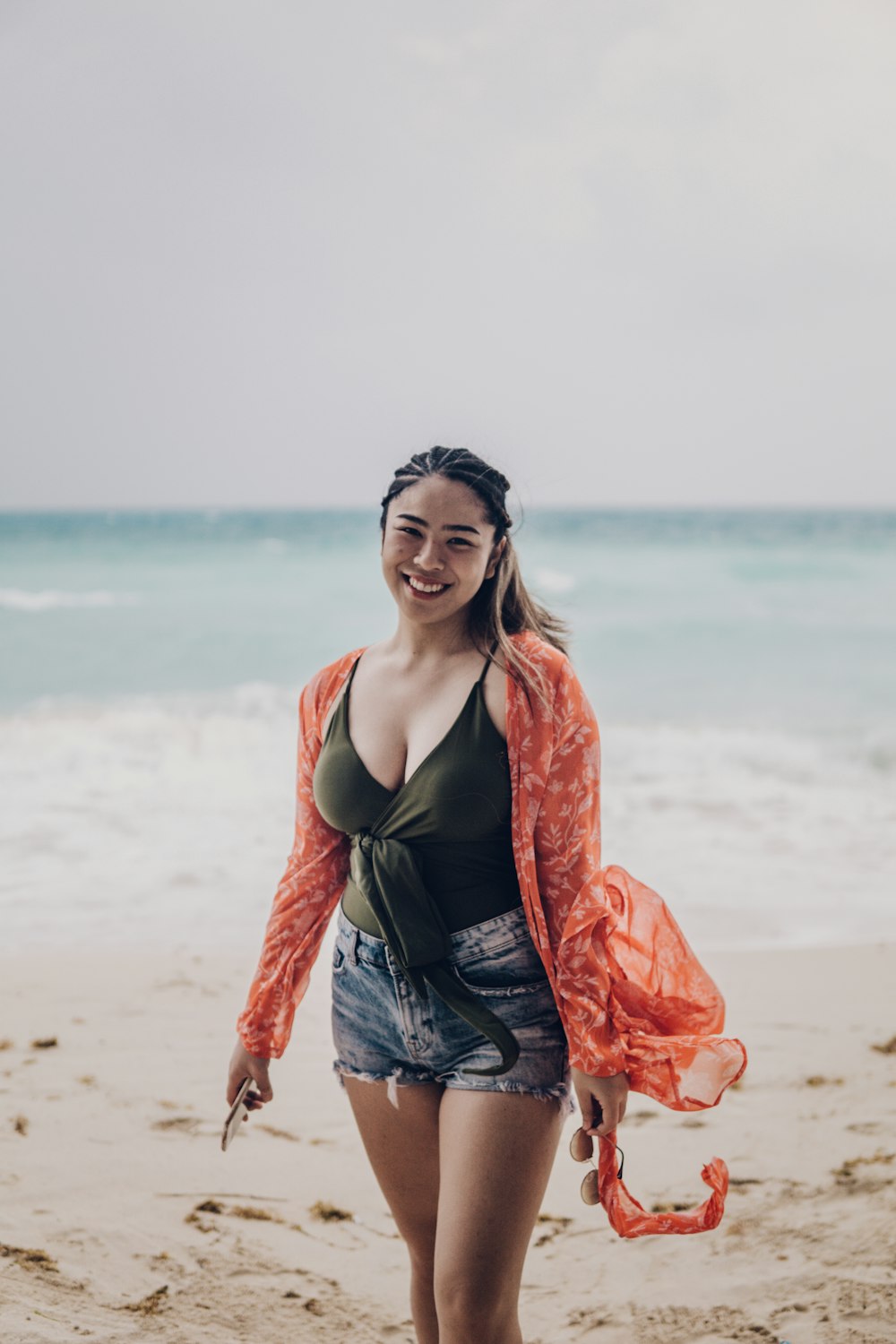 woman in black tank top and orange cardigan standing on beach during daytime