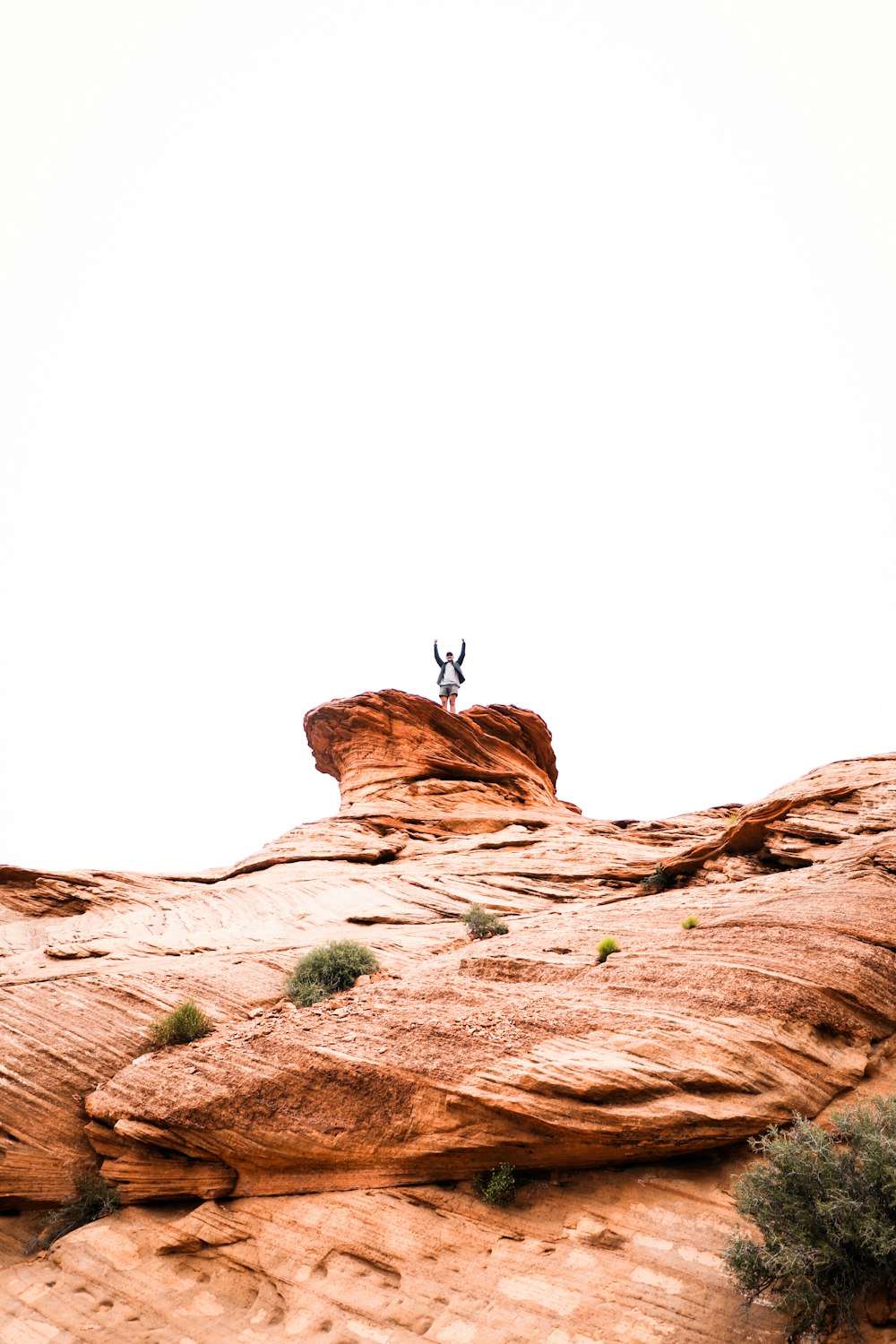 person jumping on brown rock formation during daytime