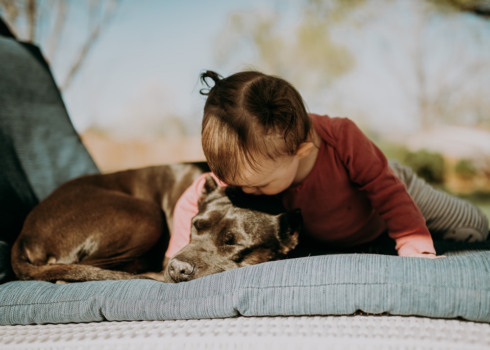 woman in brown jacket hugging black and white short coated dog