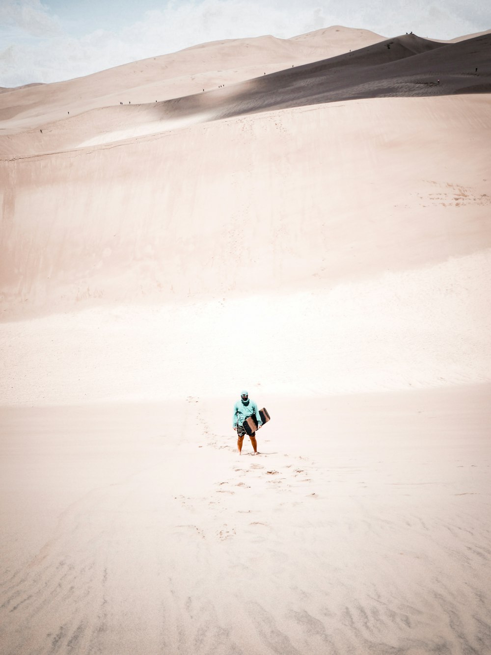 person in blue shirt and black pants walking on white sand during daytime